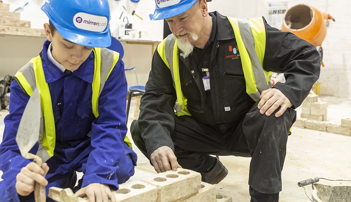 Student being instructed in brick laying